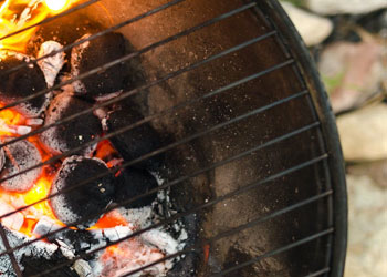 charcoals on fire under cast iron grill grates