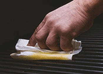 A person seasoning a Traeger smoker grill