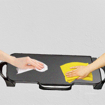 Two hands wiping an electric griddle