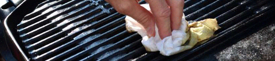 A person seasoning a charcoal grill
