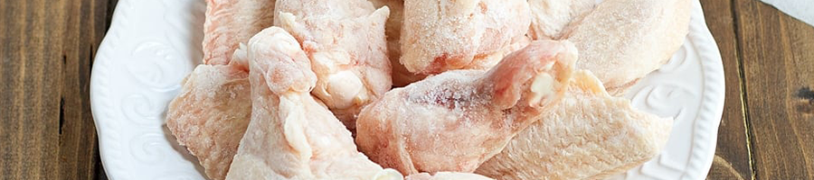 A close up image of frozen chicken wings on a counter top