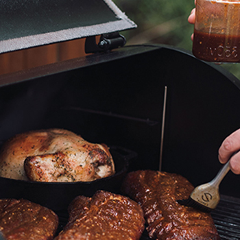 A turkey with other meats inside a pellet grill