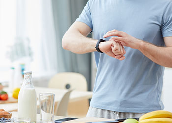 Man in the kitchen looking at his wrist watch
