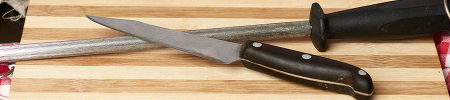 A knife and sharpening rod on a cutting board