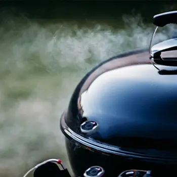 close up image of a kettle grill smoking