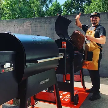 man using a griller outdoors while also giving a happy thumbs up