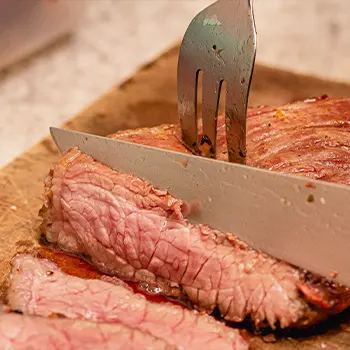 close up image of meat getting sliced by a knife and fork