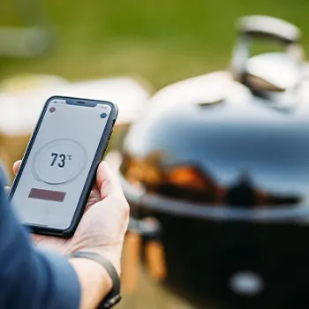 person using a phone to check temperature of grill
