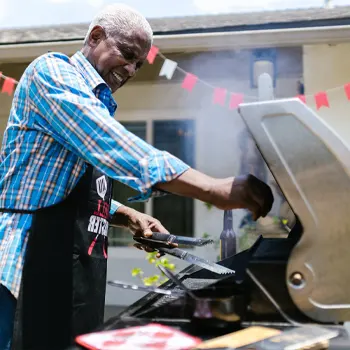 A man using an electric grill outside the back yard