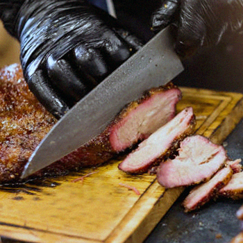 A person cutting the beef brisket on the chopping board