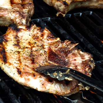 Grilled meat on a griller using tong