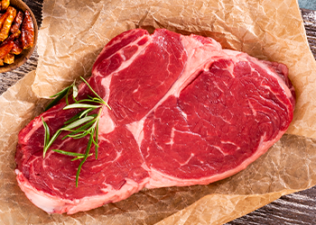 Fresh ribeye steak on wooden cutting board