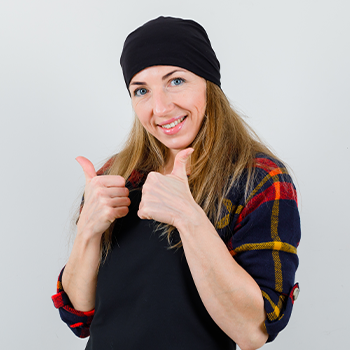 Young female cook giving thumbs up