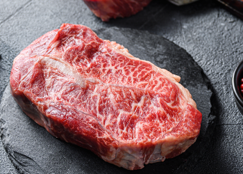 Raw blade steak on top of grey stone surface