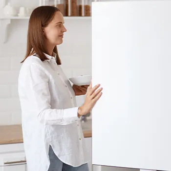 Woman putting bacon on refrigerator