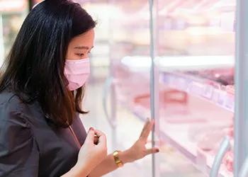 Woman choosing meat through glass door