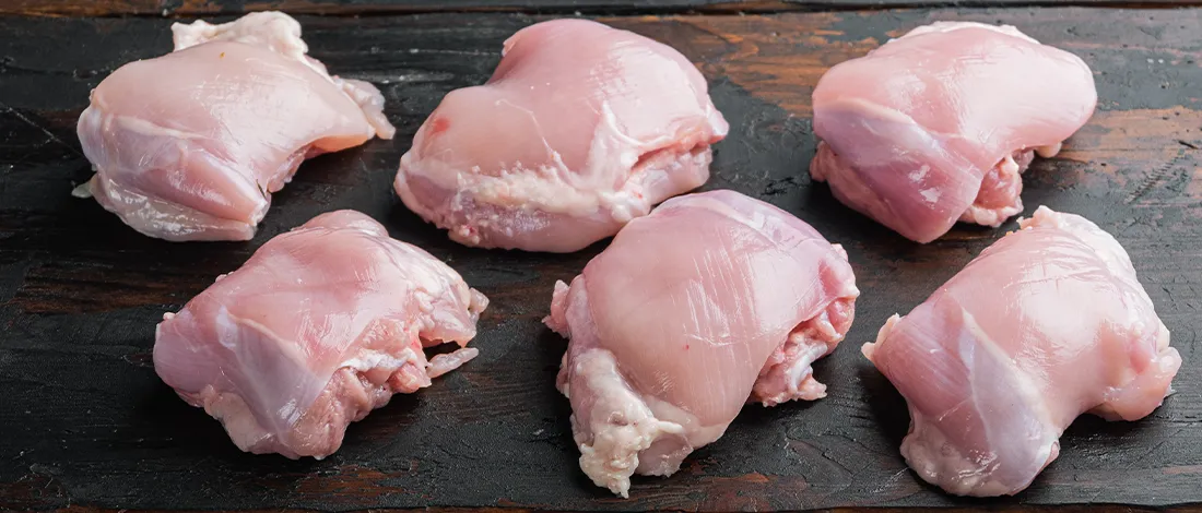 Top view of two rows of six raw chickens on a wooden table