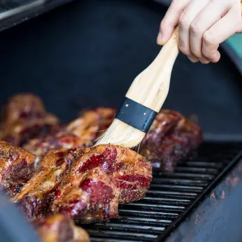Brushing meat with flavor on a grill