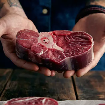 A person holding a meat cut