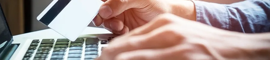 A person holding a credit card for buying online using laptop