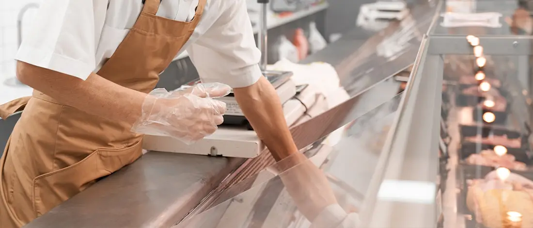 Butcher putting meat on glass counter