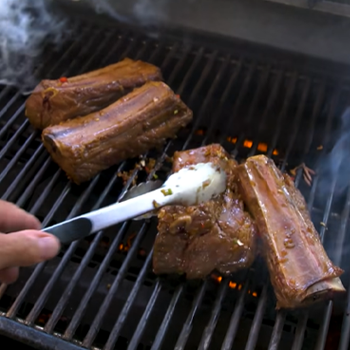 Cooking beef ribs on grill with tongs