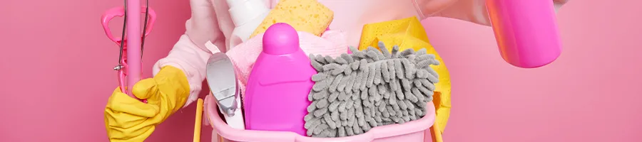 Woman holding cleaning materials with pink background