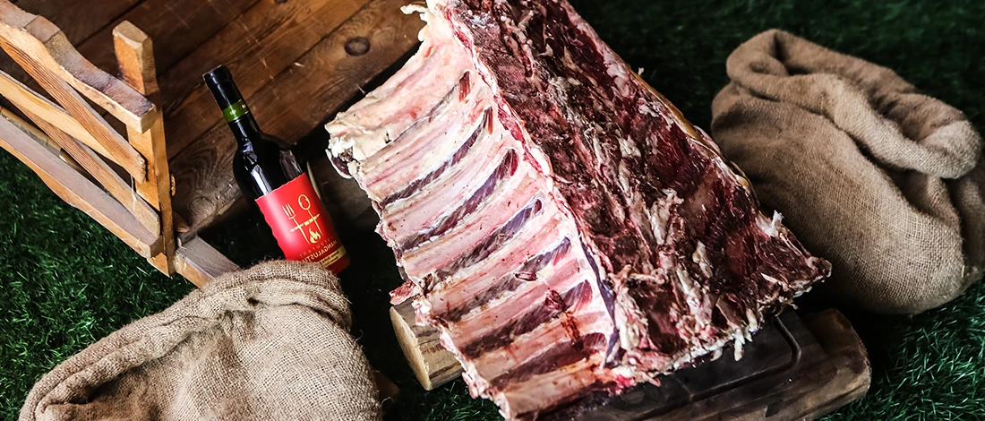 Raw beef ribs on grass with bottled red wine and sack