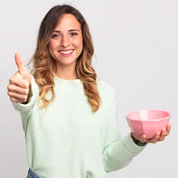 Woman holding a bowl giving thumbs up