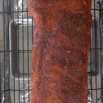 A big ribs on a grill with water pan underneath