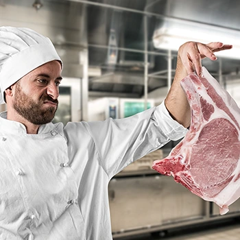 chef holding up meat with an upset face