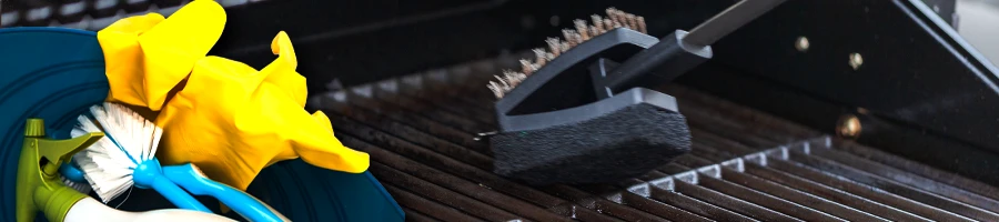 Gloves, brushes and spray in a bucket, scraping the outside of grill