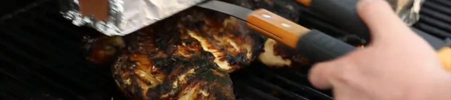 Placing an object to flatten the chicken on the grill