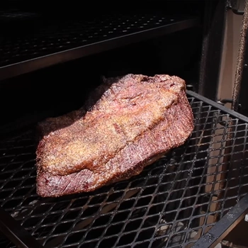 A meat inside the gravity smoker being cooked and checked