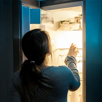 Woman opening fridge at night