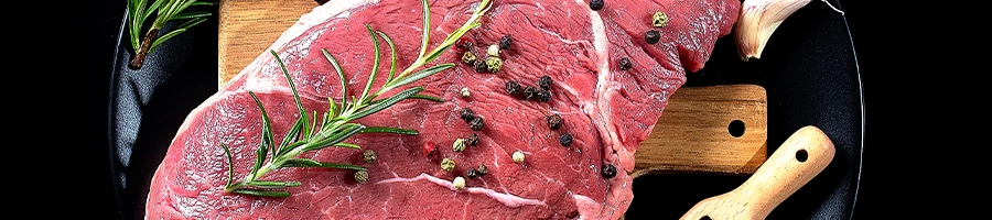 Top view of a steak with spices and wooden spoon close up image