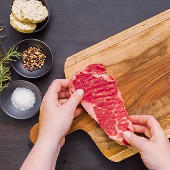 Putting New York steak on a cutting board