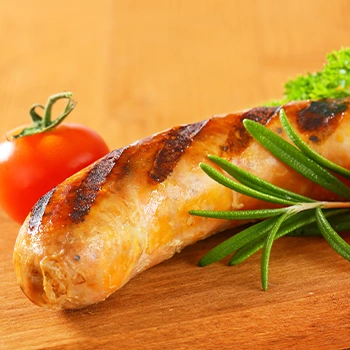 Close up image of grilled bratwurst with small tomato