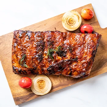 Pork ribs resting on wooden cutting board with plain white background