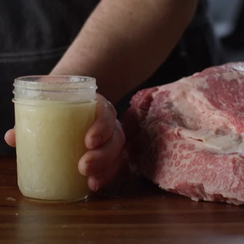 Holding the jar for beef tallow beside the brisket meat
