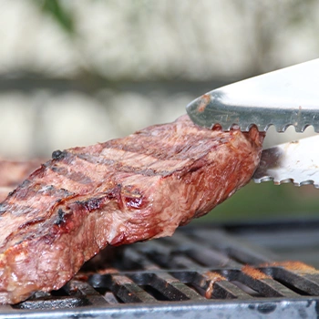 Grilling a meat using a tong