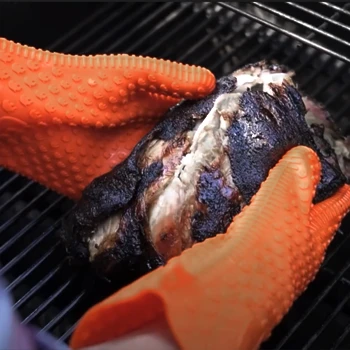 Holding a chicken meat on a grill with a barbeque glove