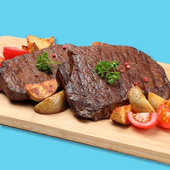 Sirloin resting on cutting board with tomatoes and potatoes