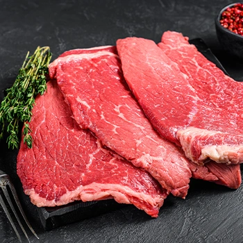 Raw steak resting on black small tray with rosemary