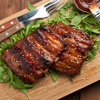 Smoked ribs on cutting board and leaves vegetable under the meat with fork