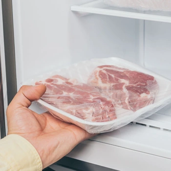 hand view of a person storing meat in the freezer