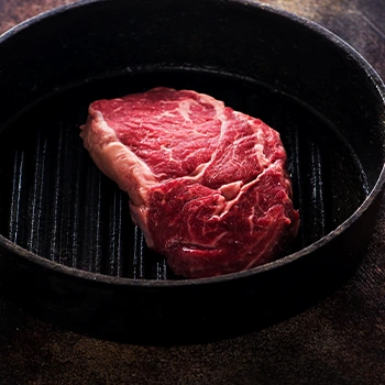 pan with raw rib eye steak