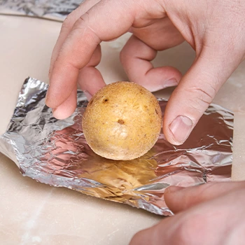 hand view of a person wrapping potato in foil