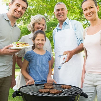 A family smiling in camera while using portable rv grill