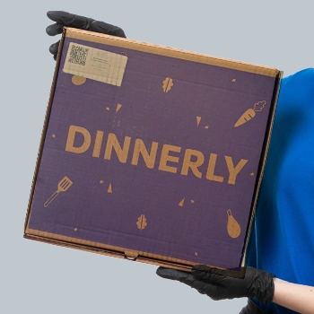 A delivery guy holding a Dinnerly box